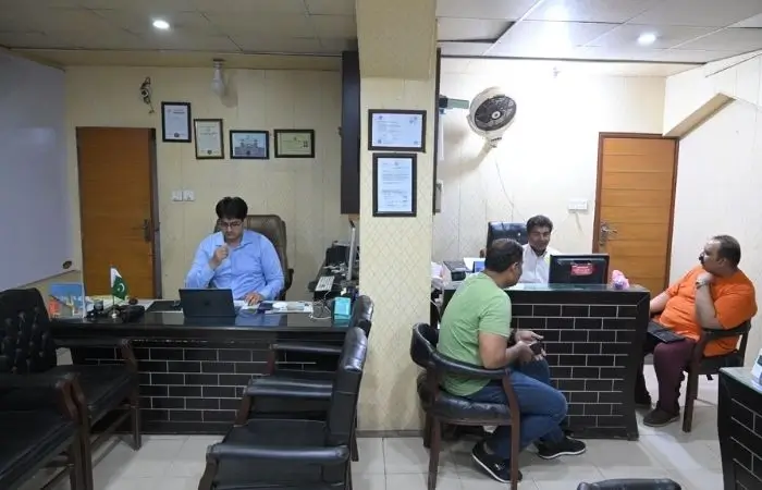 گوجرانوالہ میں دی فلائٹ سنٹر کے دفتر کے اندر اسٹاف سے بات کرتے ہوئے واک اِن کلائنٹس